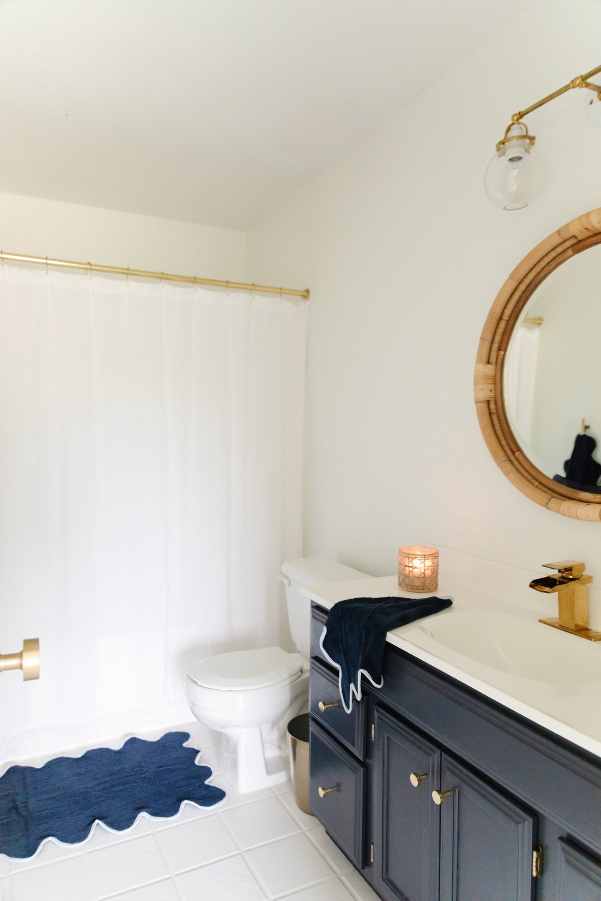 A nautical-themed bathroom with black cabinets and a round mirror.