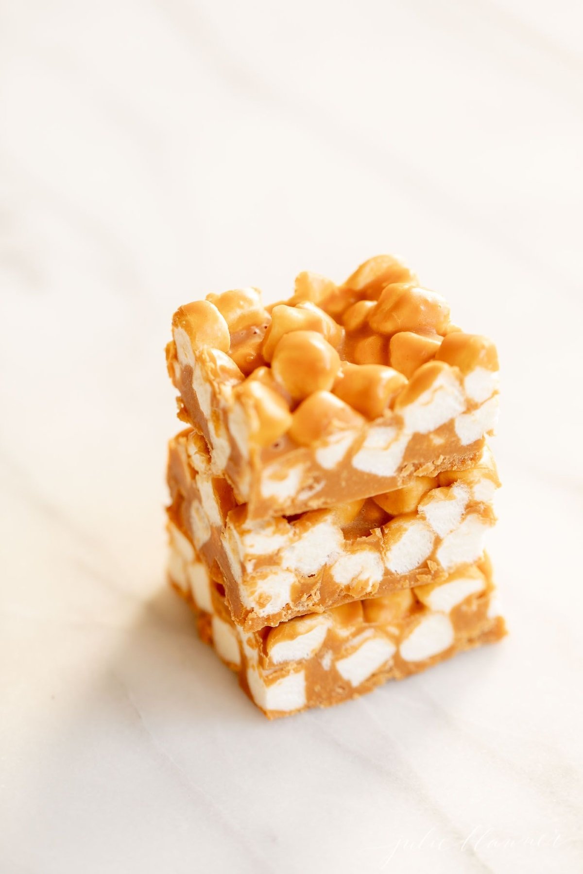 A stack of butterscotch peanut butter marshmallow bars on a marble countertop.