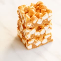 A stack of butterscotch peanut butter marshmallow bars on a marble countertop.