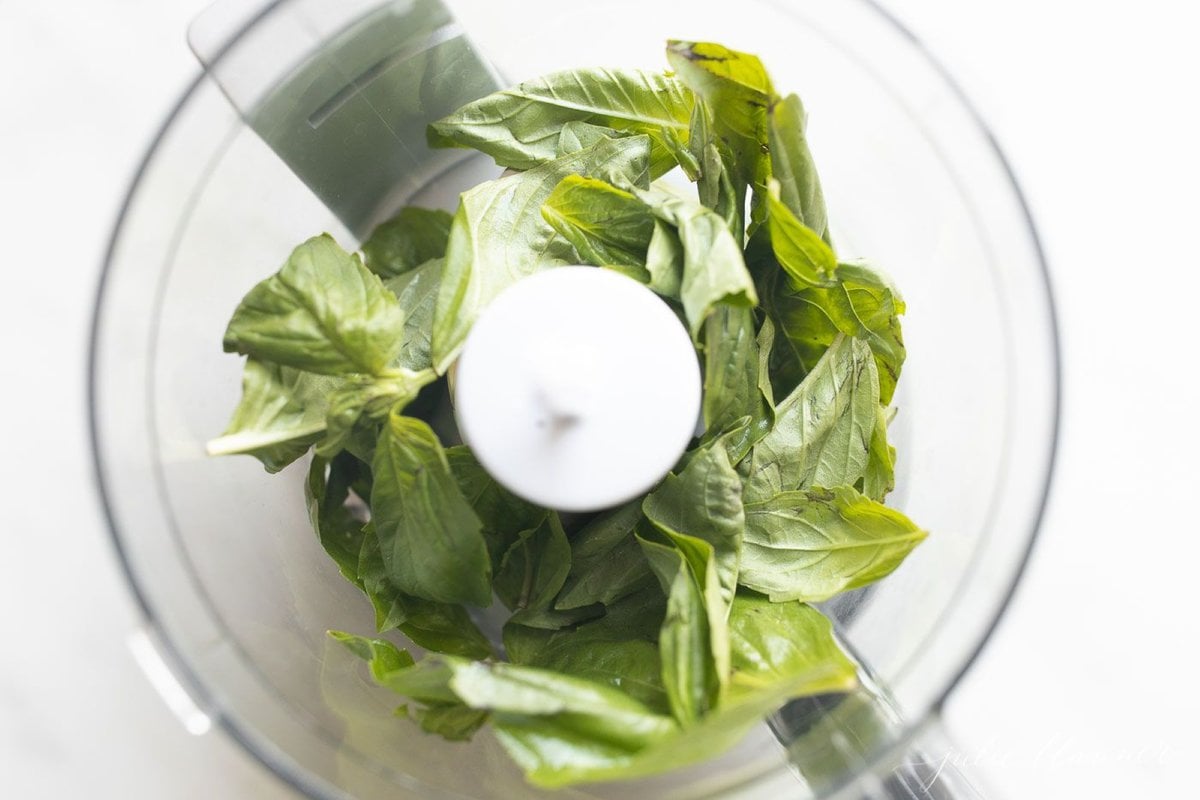 Basil and mayo inside a food processor for a pesto style basil aioli recipe.