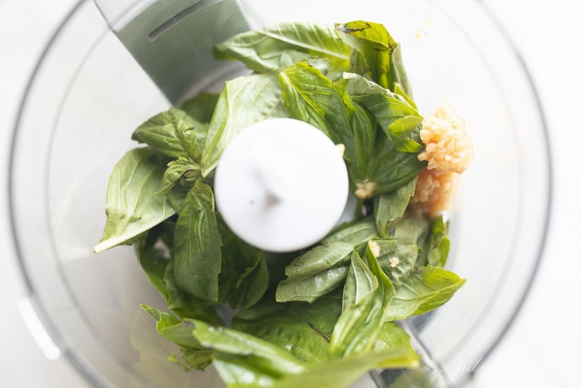 Basil and mayo inside a food processor for a pesto style basil aioli recipe.