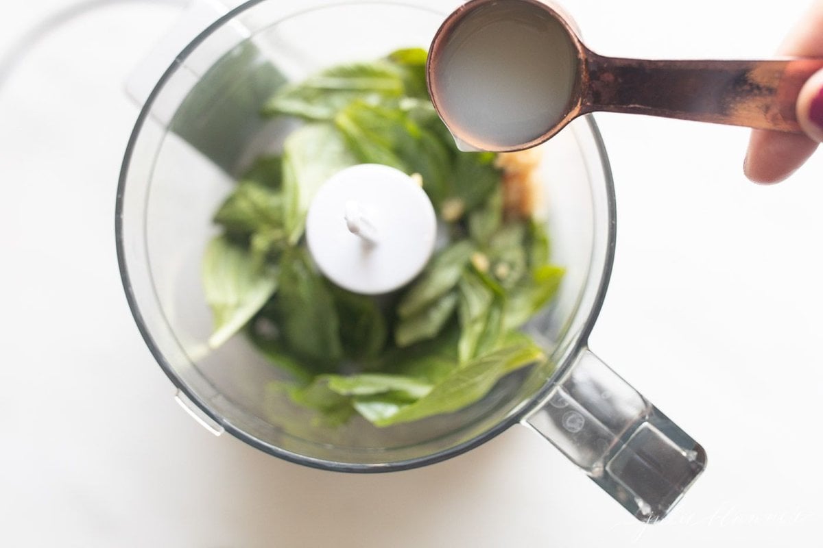 Basil and mayo inside a food processor for a pesto style basil aioli recipe.