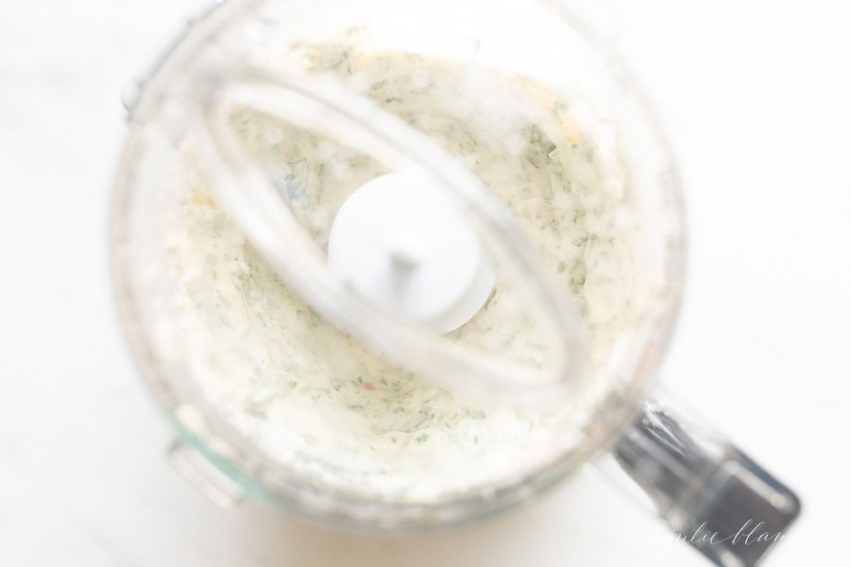 Basil and mayo inside a food processor for a pesto style basil aioli recipe.