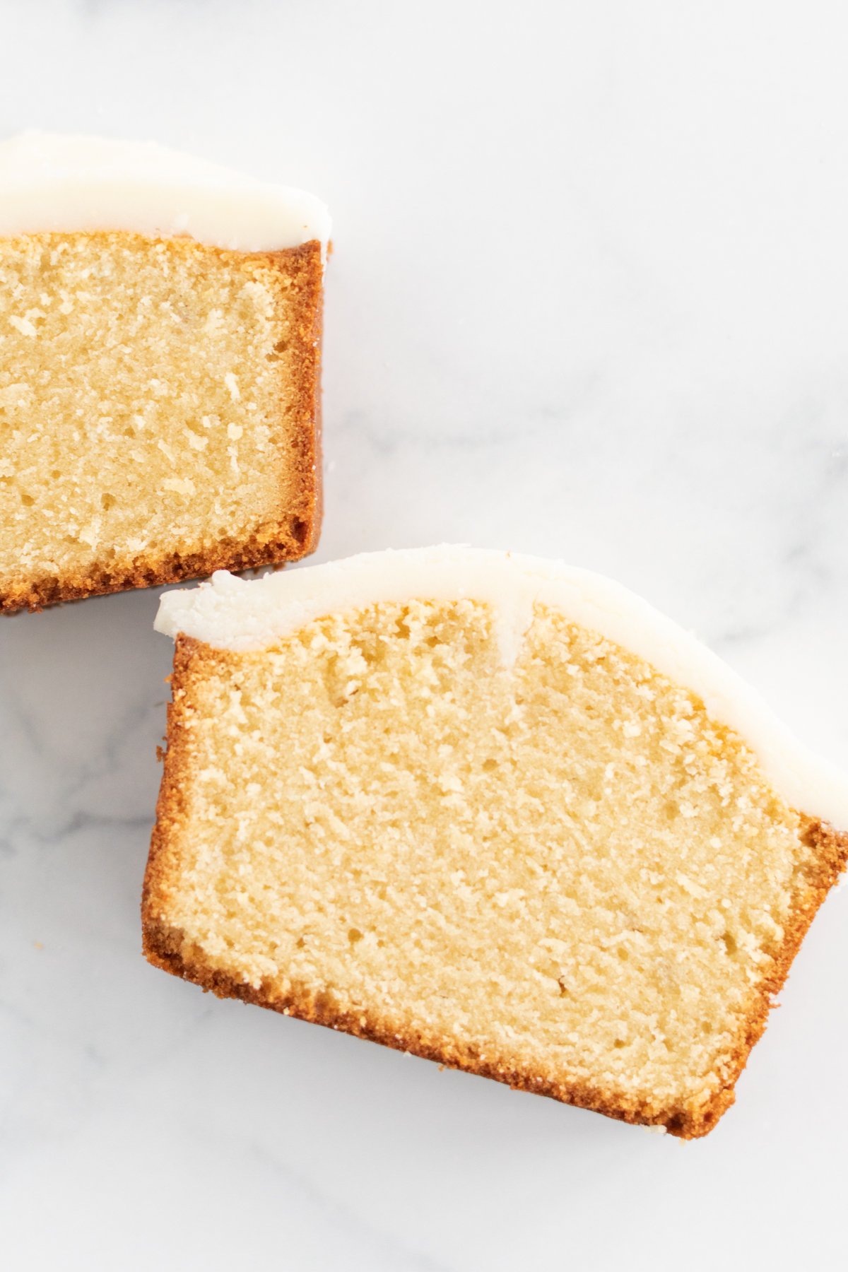 Two slices of lemon pound cake on a marble surface, showcasing the perfect pound cake recipe.