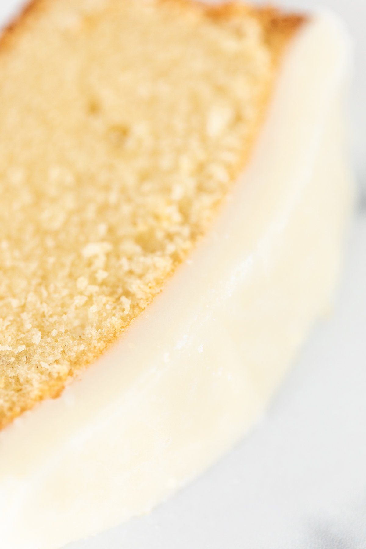 A slice of iced pound cake on a white plate.