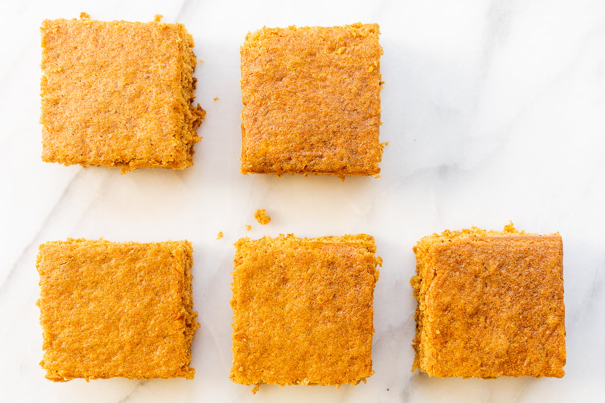 Squares of a pumpkin bar recipe laid out on a marble countertop.