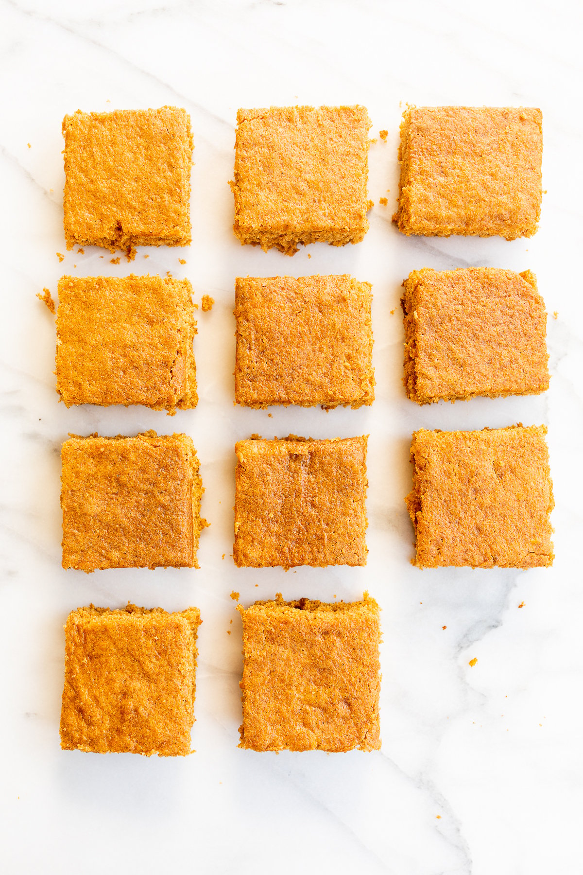 Squares of a pumpkin bar recipe laid out on a marble countertop.