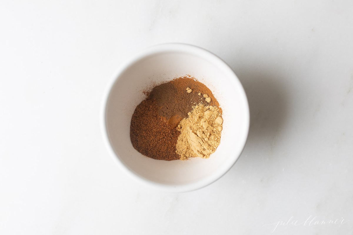 A white bowl full of spices for a pumpkin pie spice recipe.