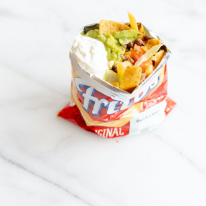 Tasty nachos in a bag topped with sour cream and guacamole.