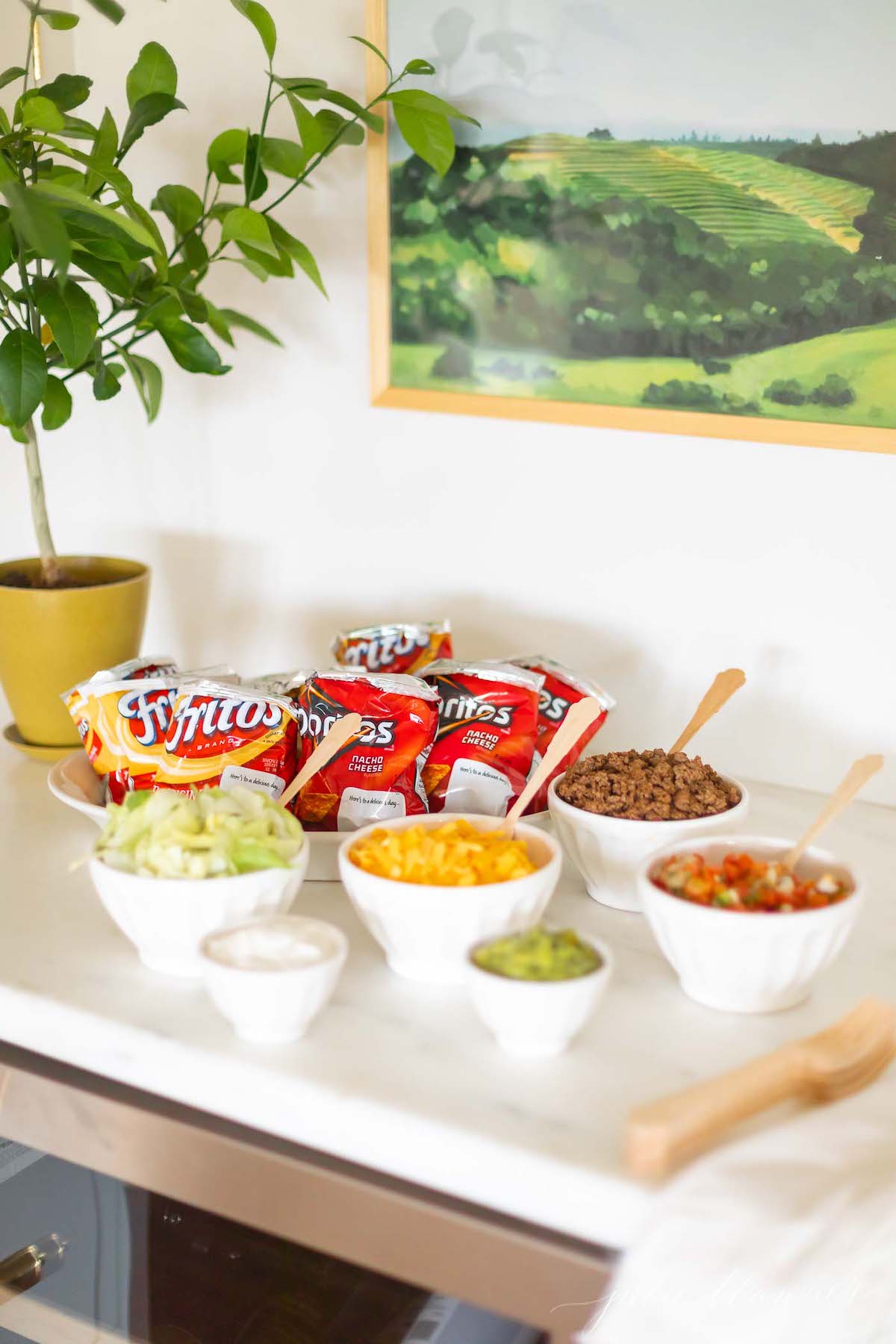 A walking taco bar set up with a green and blue painting in the background.