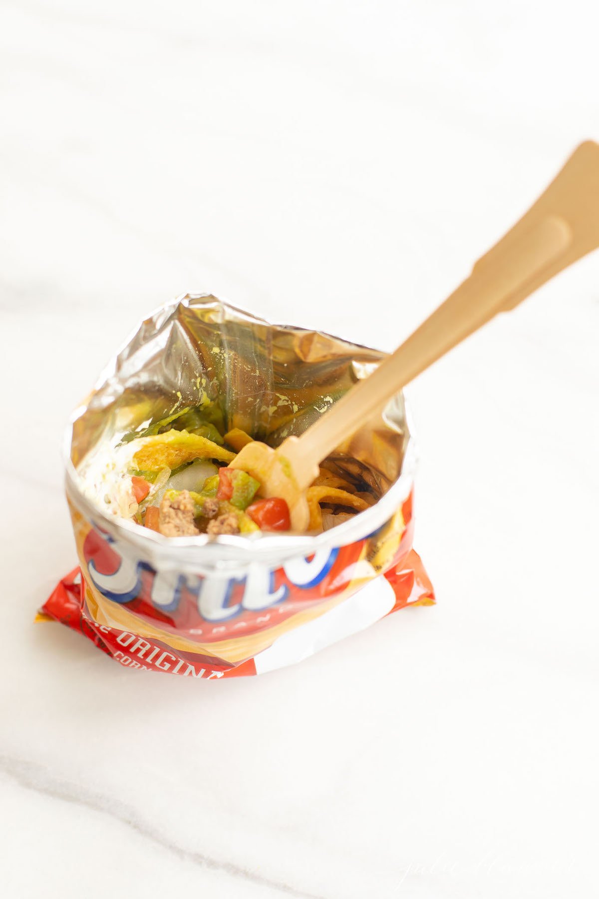 A Fritos bag of a walking tacos recipe with sour cream and guacamole.