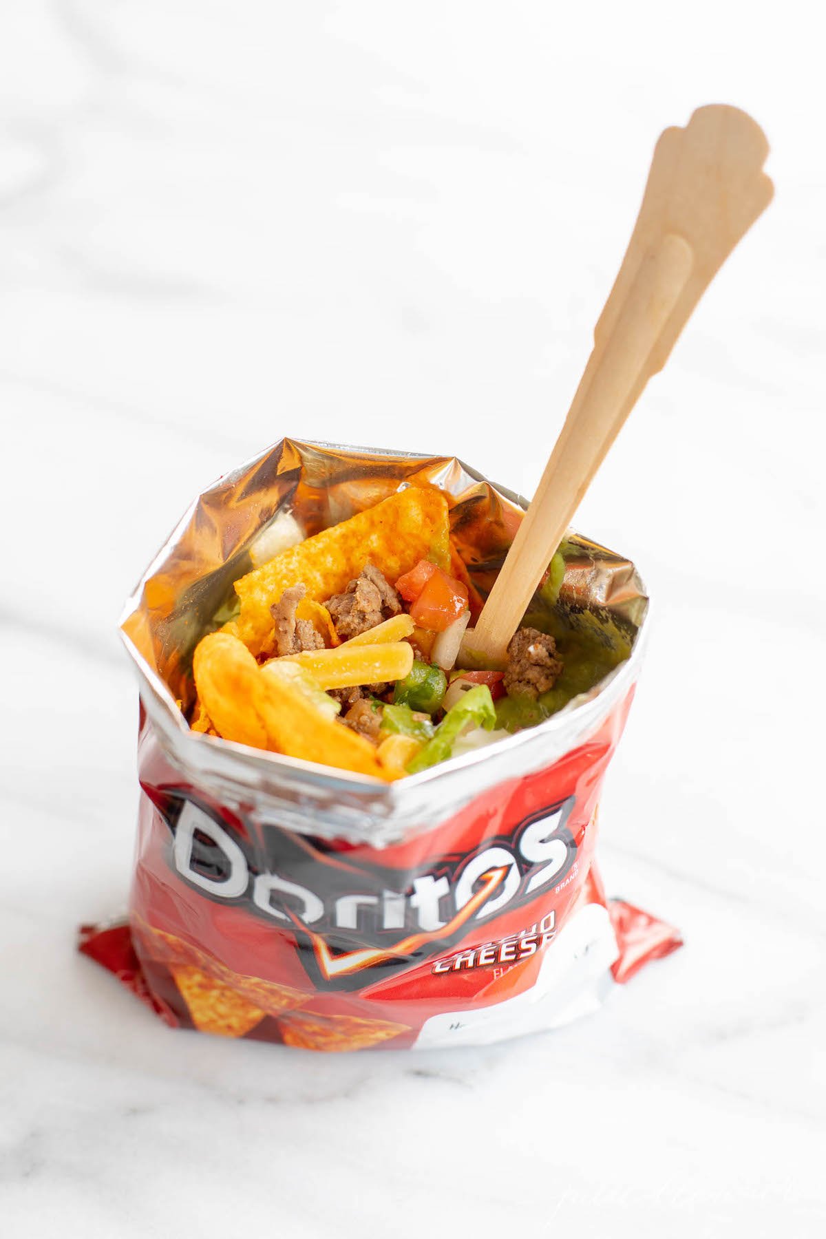 A bag of Doritos chips transformed into a "walking taco" with the addition of a wooden spoon.