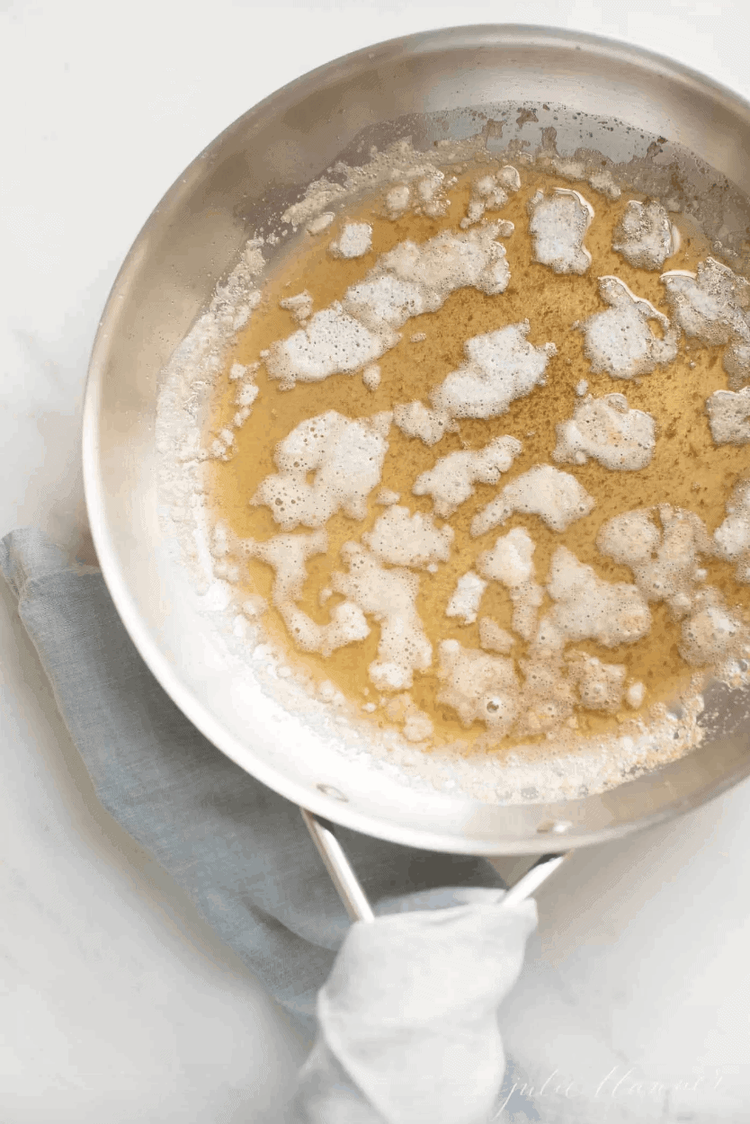 brown butter in a saucepan with blue napkin wrapped around handle