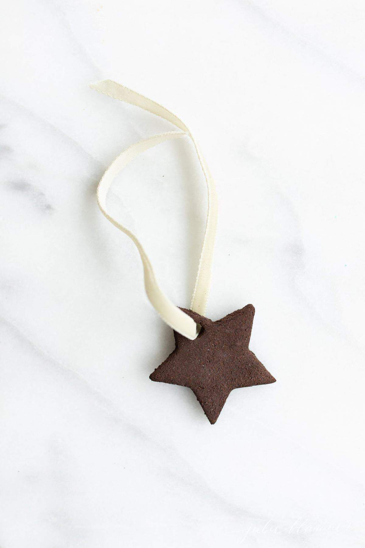 A single star handmade ornament on a marble surface.