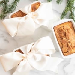 Small loaves of cinnamon bread, tied with ivory ribbon on a marble countertop for a Christmas gift.