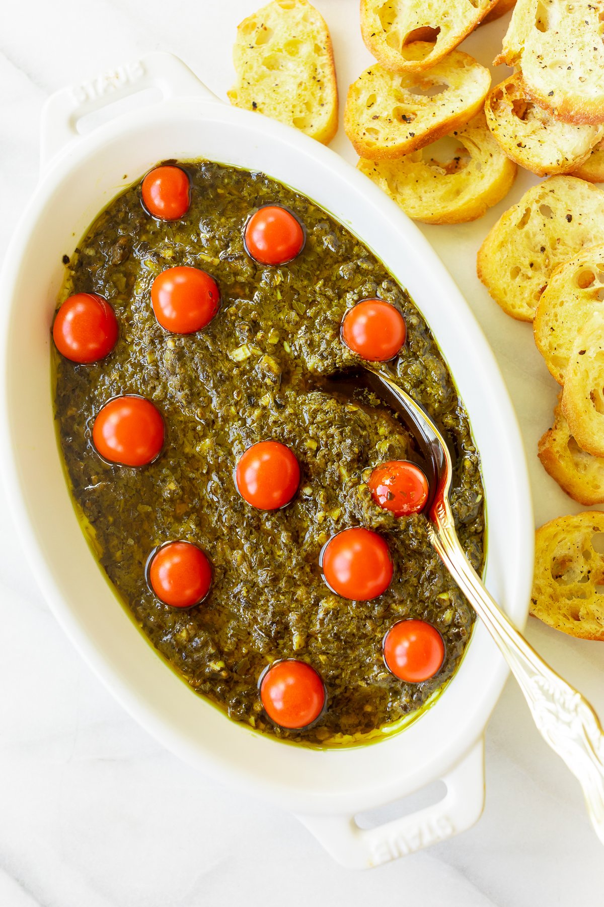 A white bowl of pesto dip with tomatoes and bread, the perfect easy appetizer dip for any occasion.