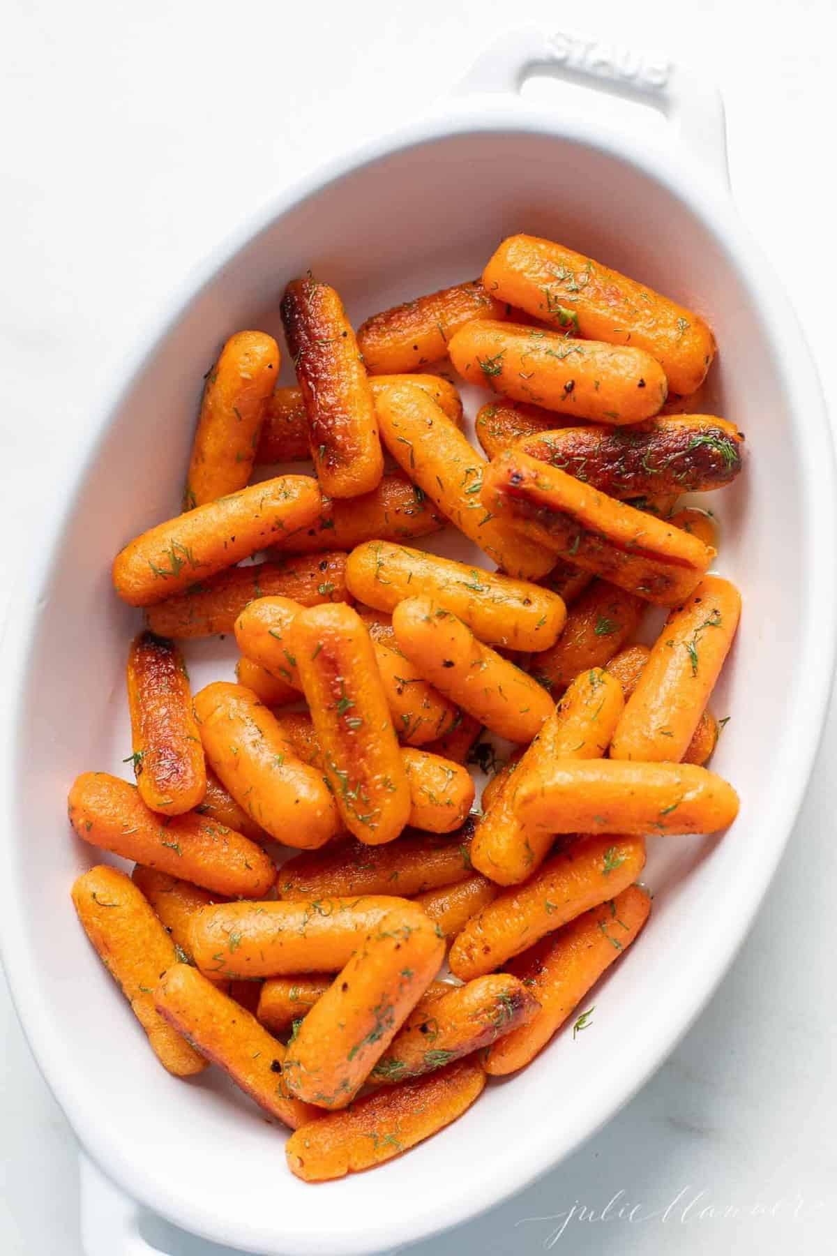 White oval serving platter with roasted baby carrots.