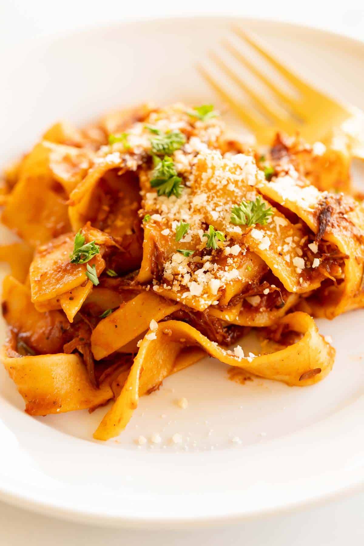 A close up of beef ragu, topped with parsley and parmesan.