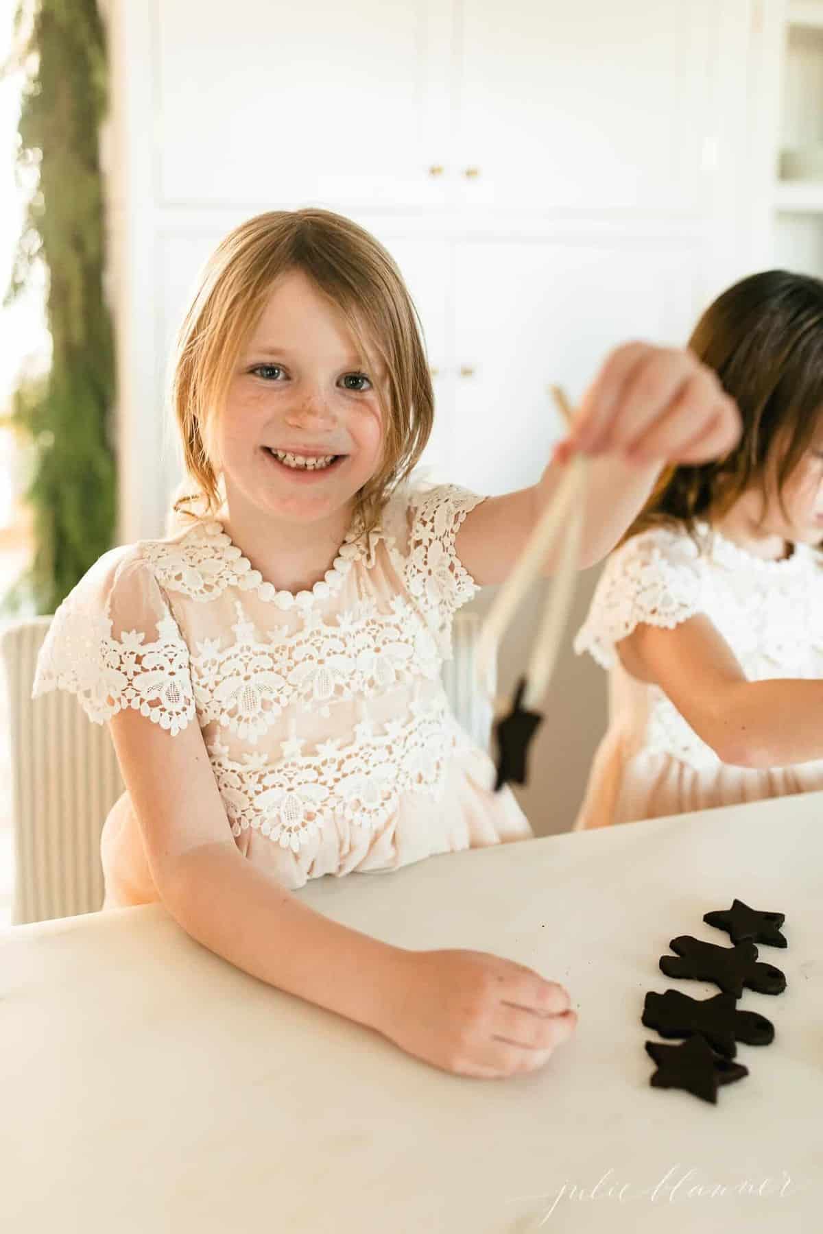 little girl threading ribbon through a cinnamon ornament.