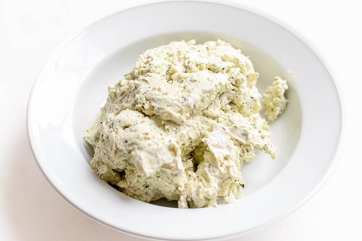 A bowl with ingredients for a pesto cheese ball