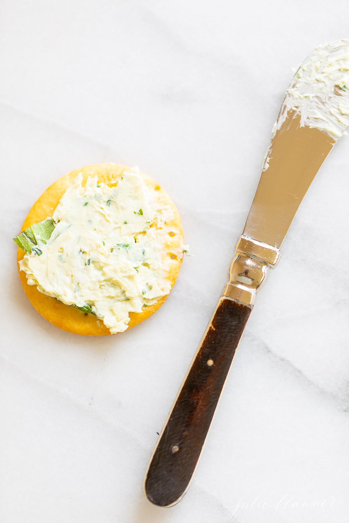 A spatula with pesto cheese on a marble countertop.