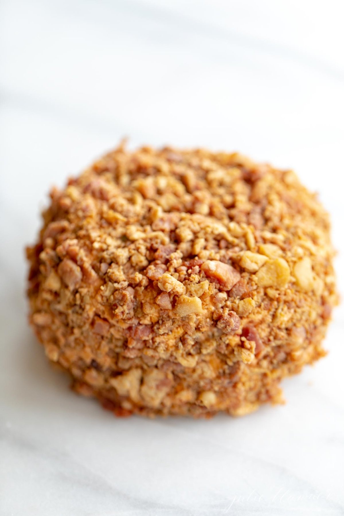 A reindeer cheeseball sitting on a marble surface.