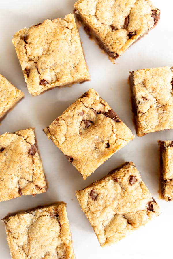 salted caramel chocolate chip cookie bars cut into squares on a white surface.