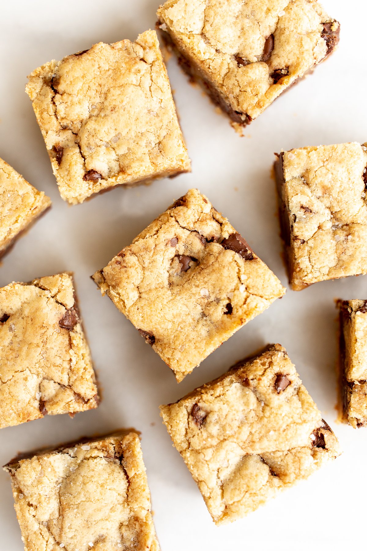 salted caramel chocolate chip cookie bars cut into squares on a white surface.