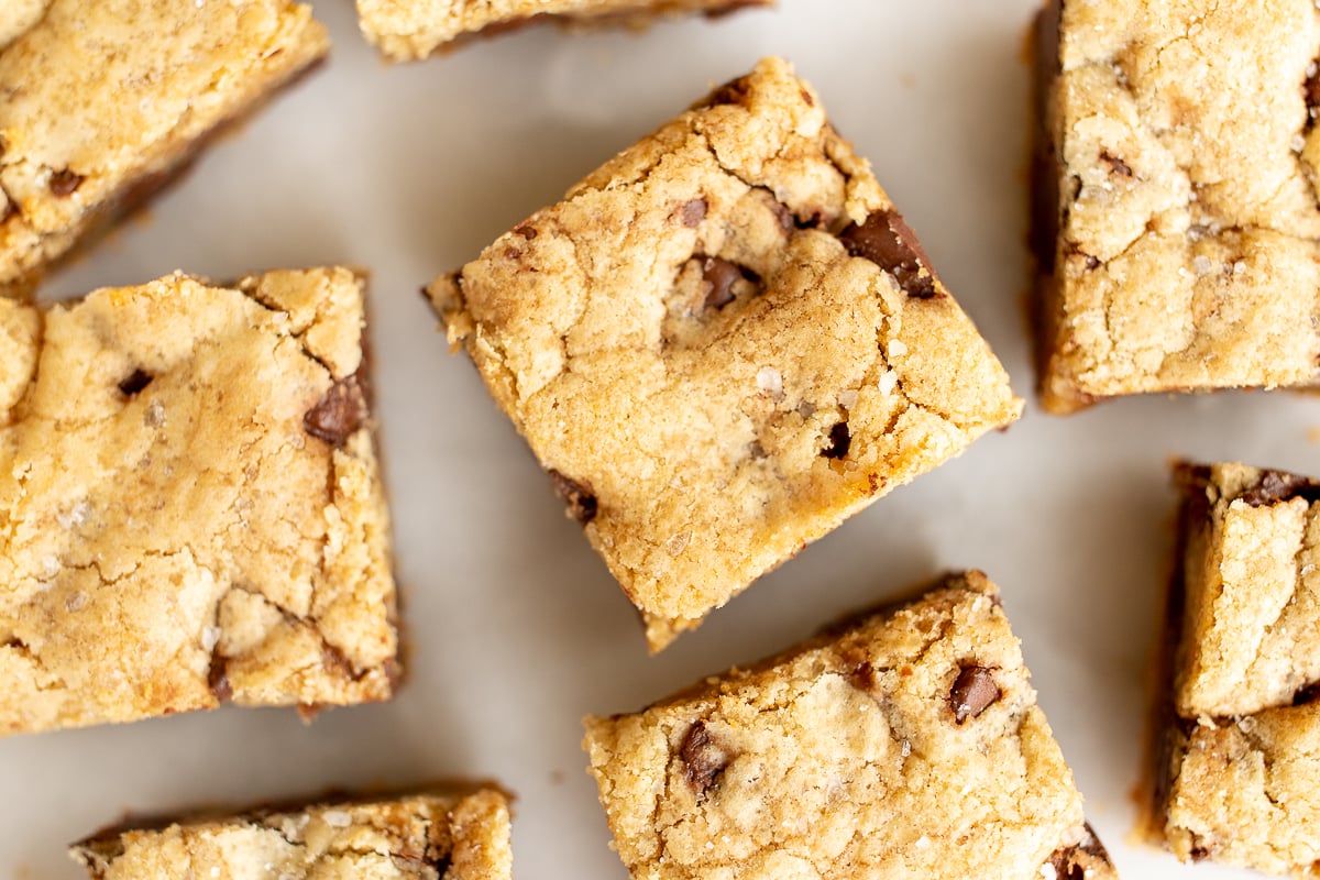 Salted caramel chocolate chip cookie bars cut into squares on a white surface.