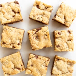 Salted caramel chocolate chip cookie bars cut into squares on a white surface.