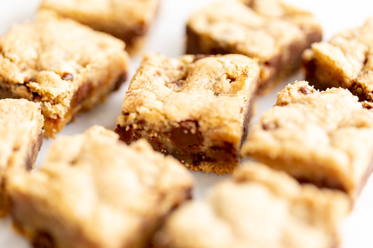 Salted caramel chocolate chip cookie bars cut into squares on a white surface.