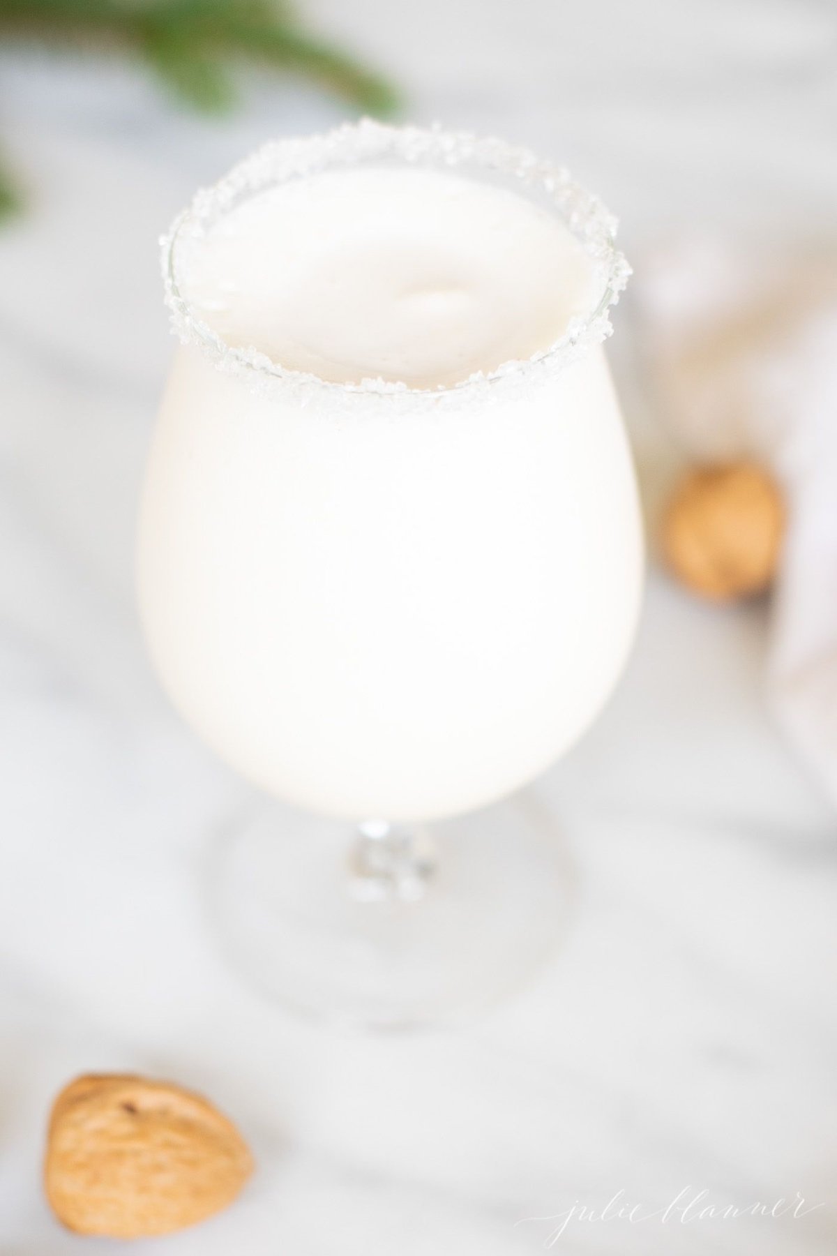 An ice cream and amaretto snowball cocktail in a stemmed glass, on a marble countertop.