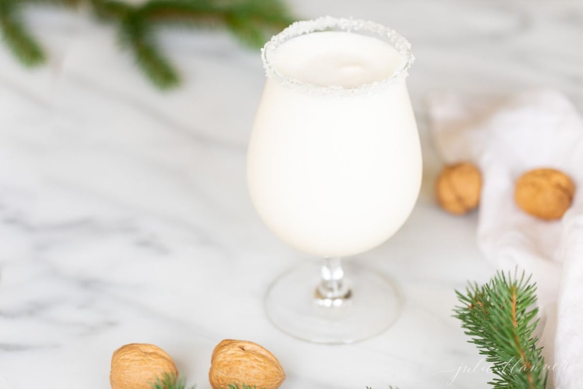 An ice cream and amaretto snowball cocktail in a stemmed glass, on a marble countertop.