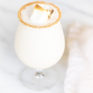 An ice cream and amaretto snowball cocktail in a stemmed glass, on a marble countertop.