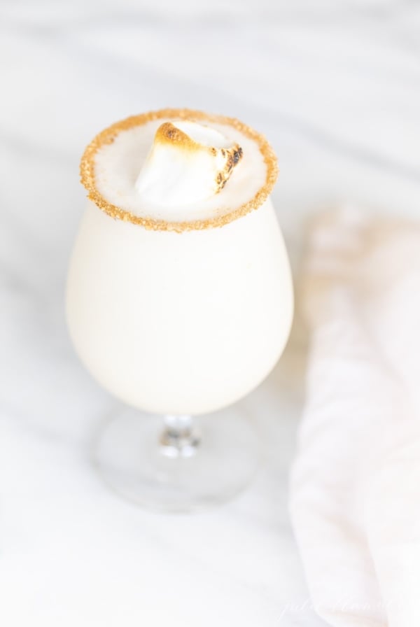 An ice cream and amaretto snowball cocktail in a stemmed glass, on a marble countertop.