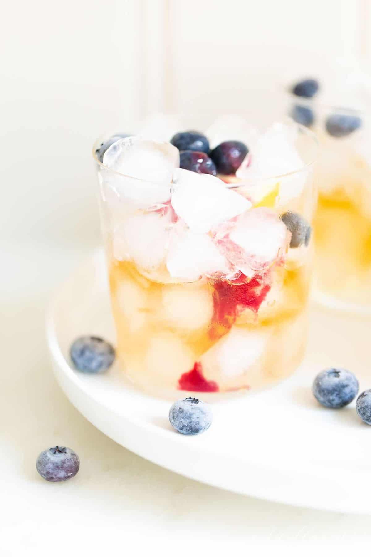 Clear glass with blueberries and ice, whiskey at the bottom.