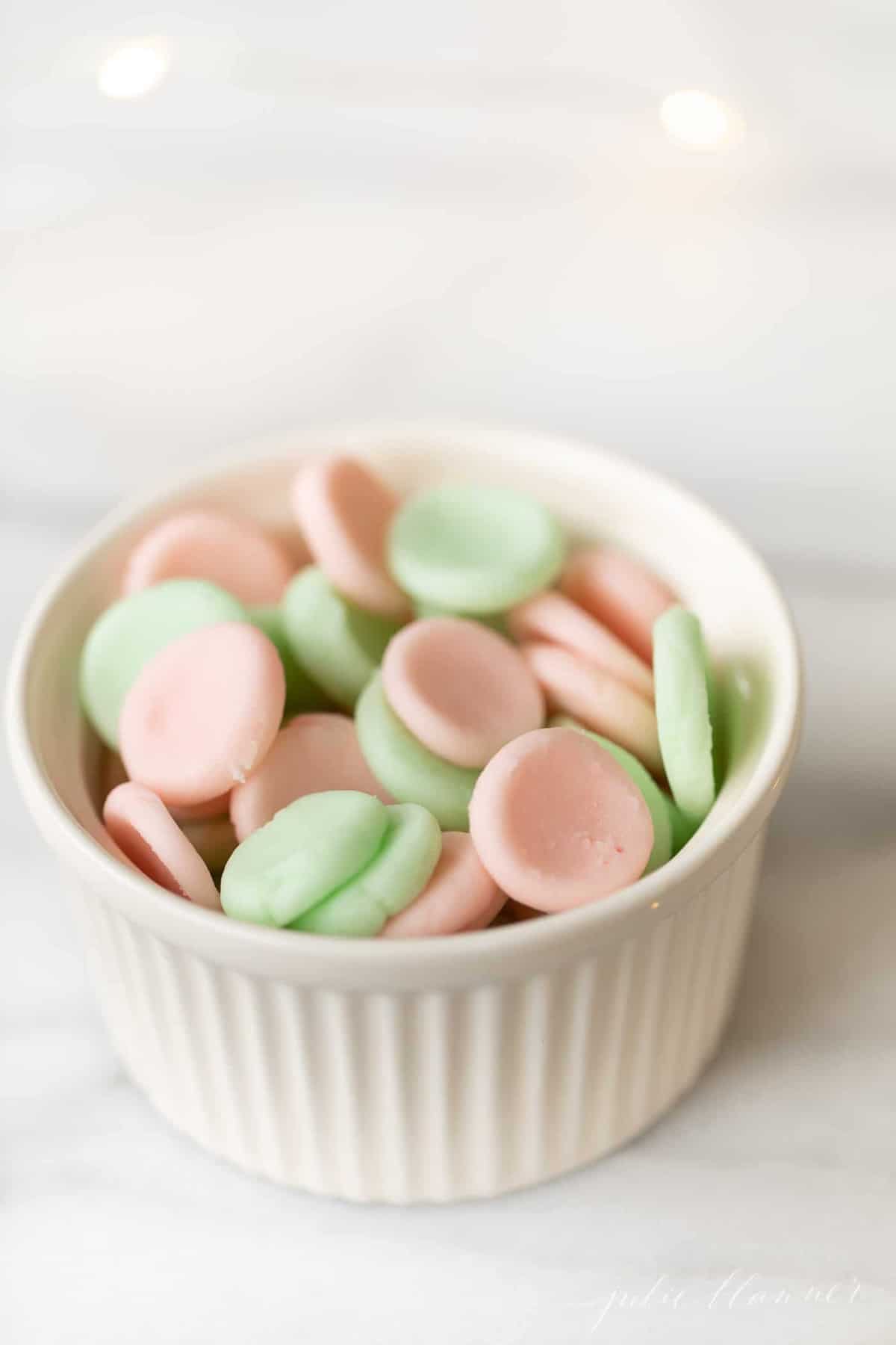 Green an pink candies in a white ramekin