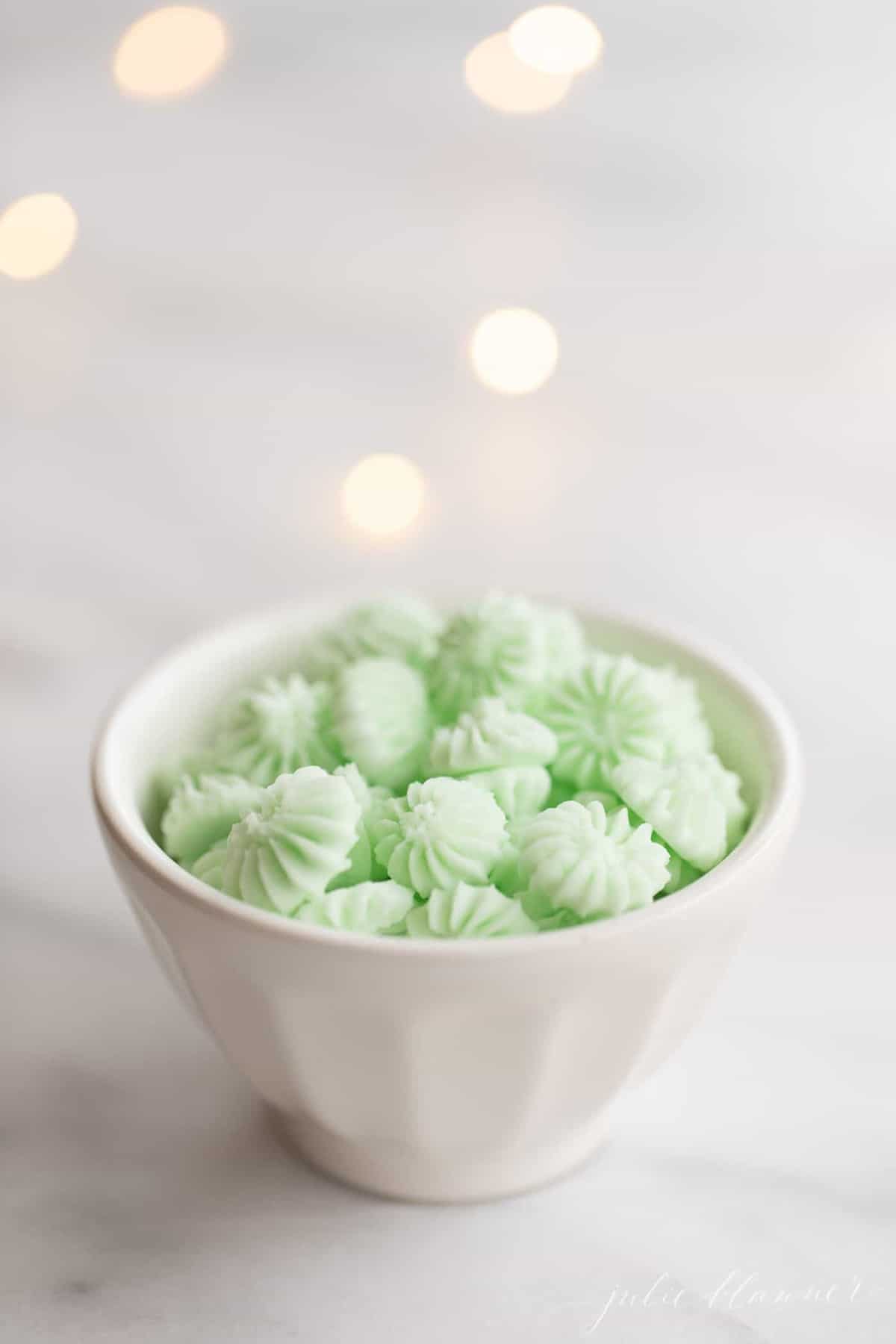 Green cream cheese mints in a small white bowl