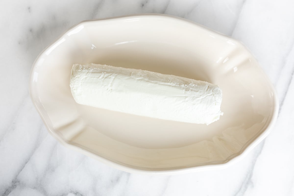 A roll of goat cheese in a white bowl.