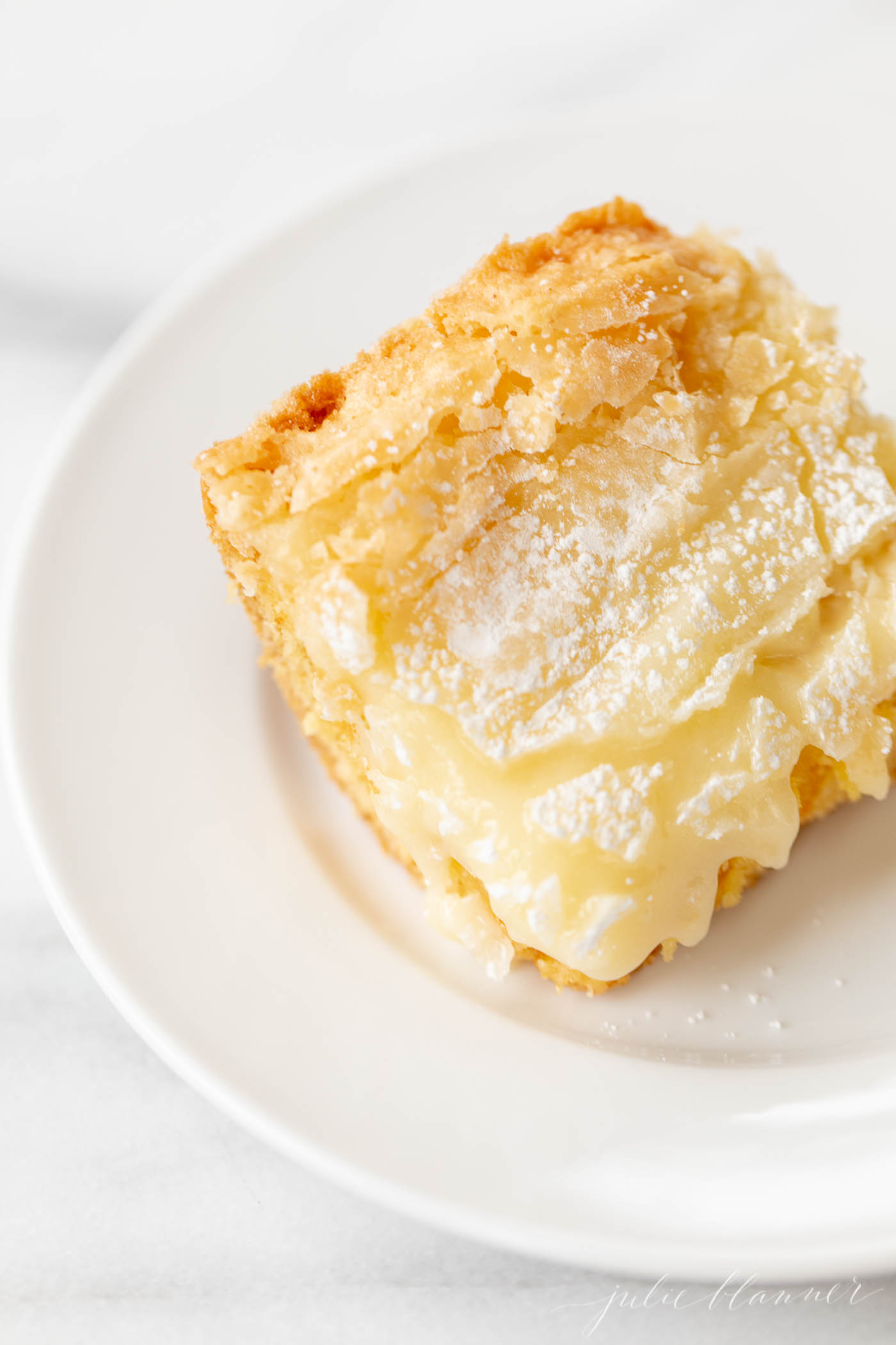 A slice of gooey butter cake on a white plate.