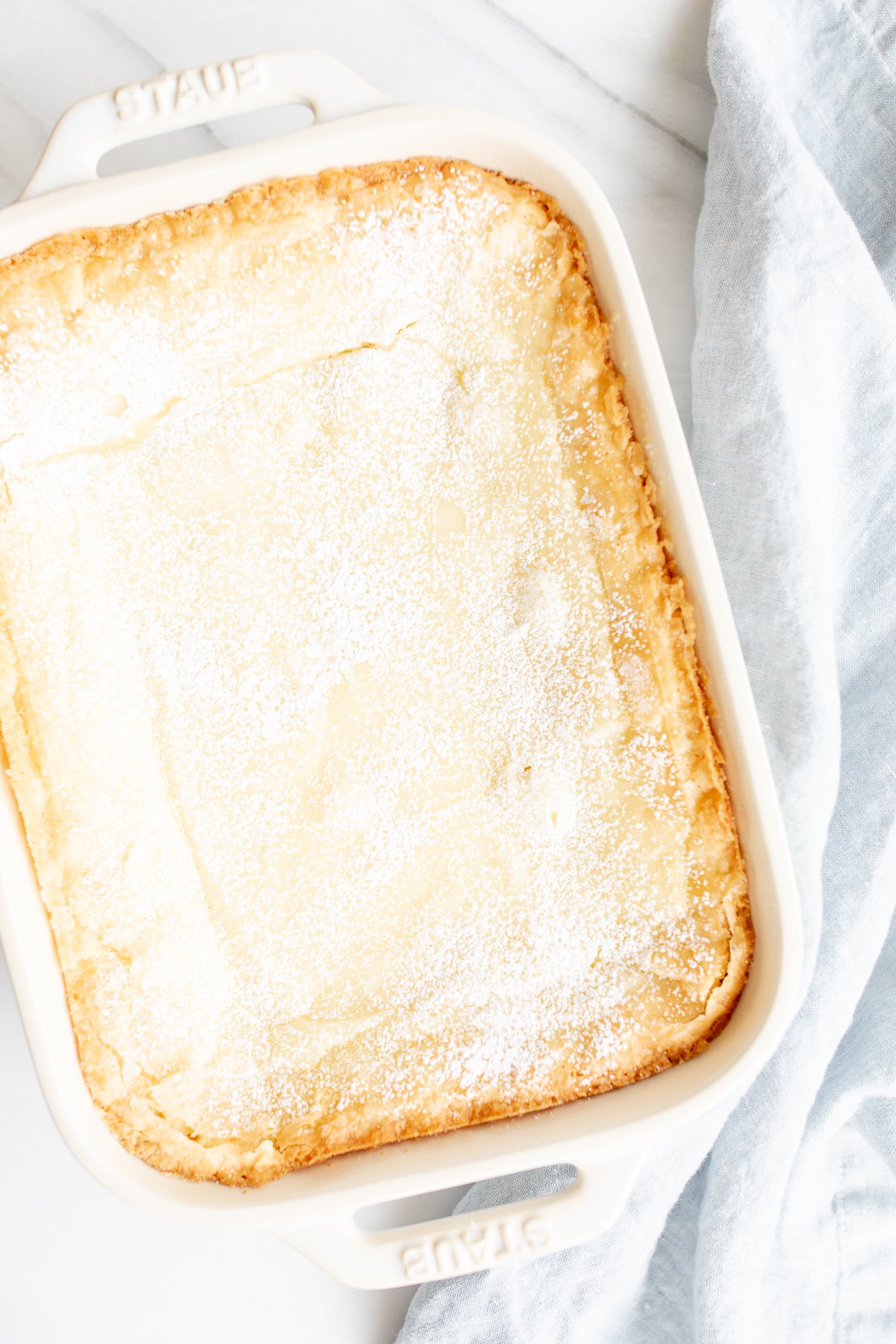 A white rectangular baking dish filled with a homemade gooey butter cake.