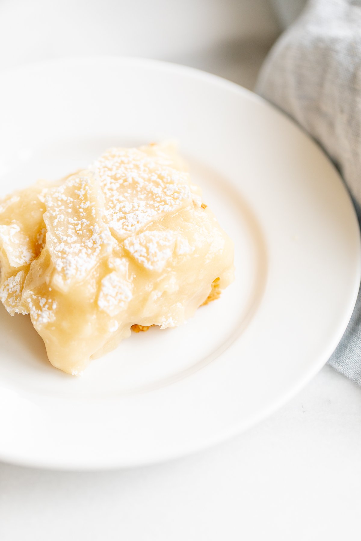 A slice of gooey butter cake on a white plate.