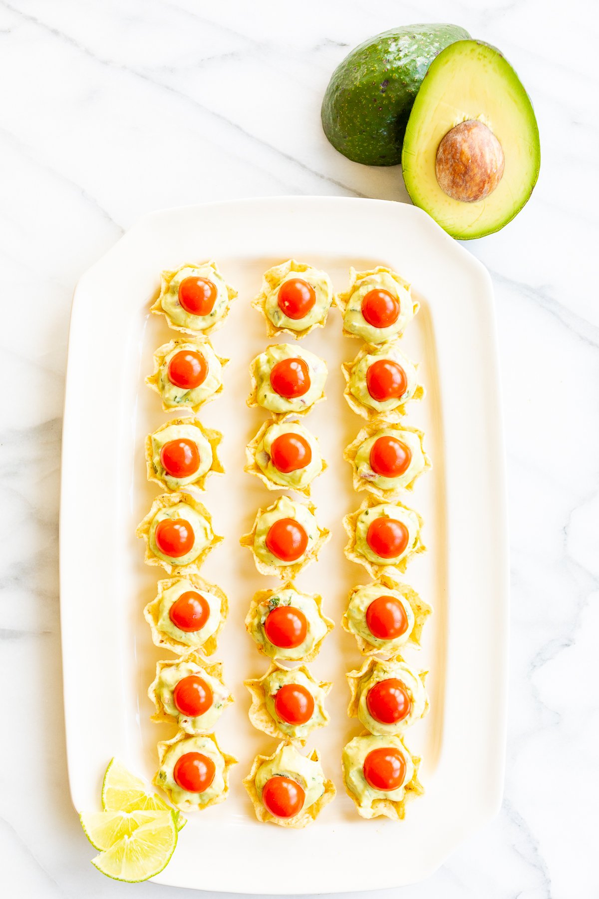 Guacamole cups with avocados on a white plate.