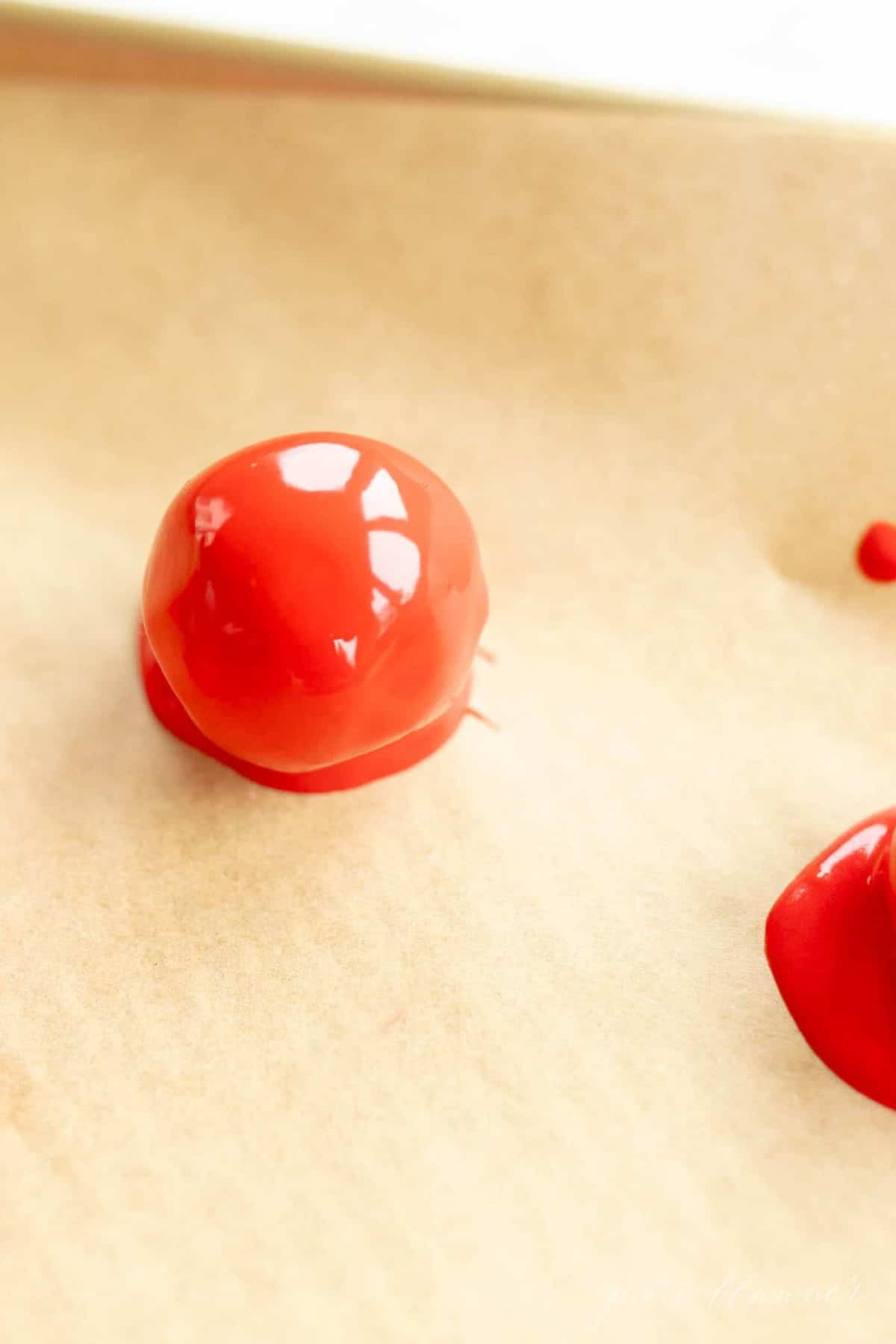 red chocolate covered cookie dough truffle on parchment lined cookie sheet