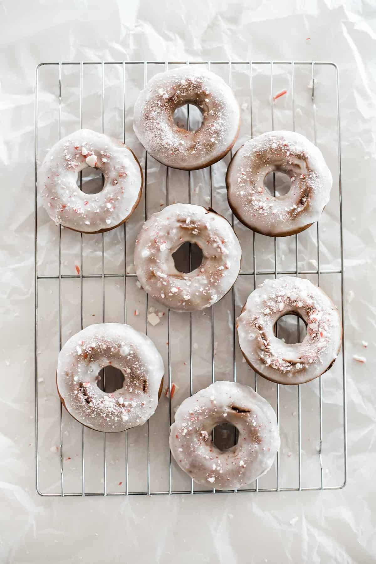 Peppermint-infused donuts, adorned with colorful sprinkles, resting on a cooling rack.