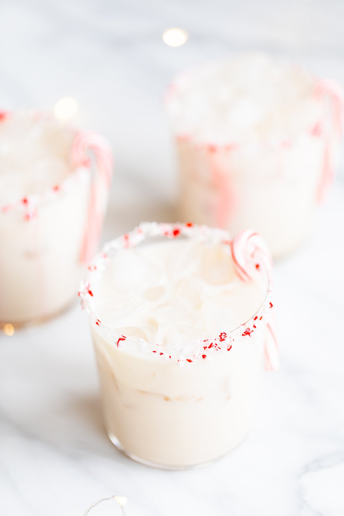 Three cups of peppermint-flavored iced drinks with candy canes on top.