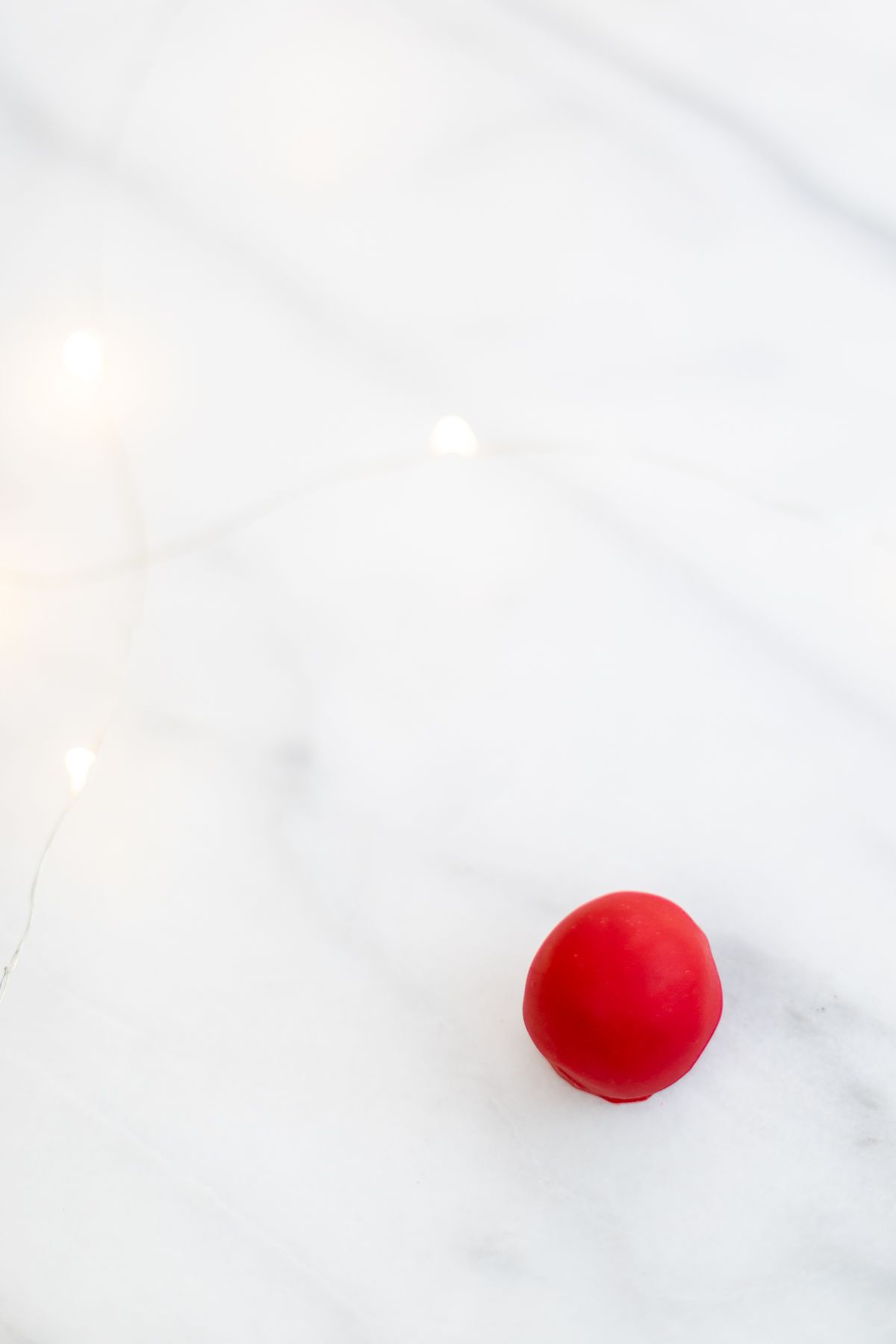 A red no bake Christmas rudolph nose on a marble surface.