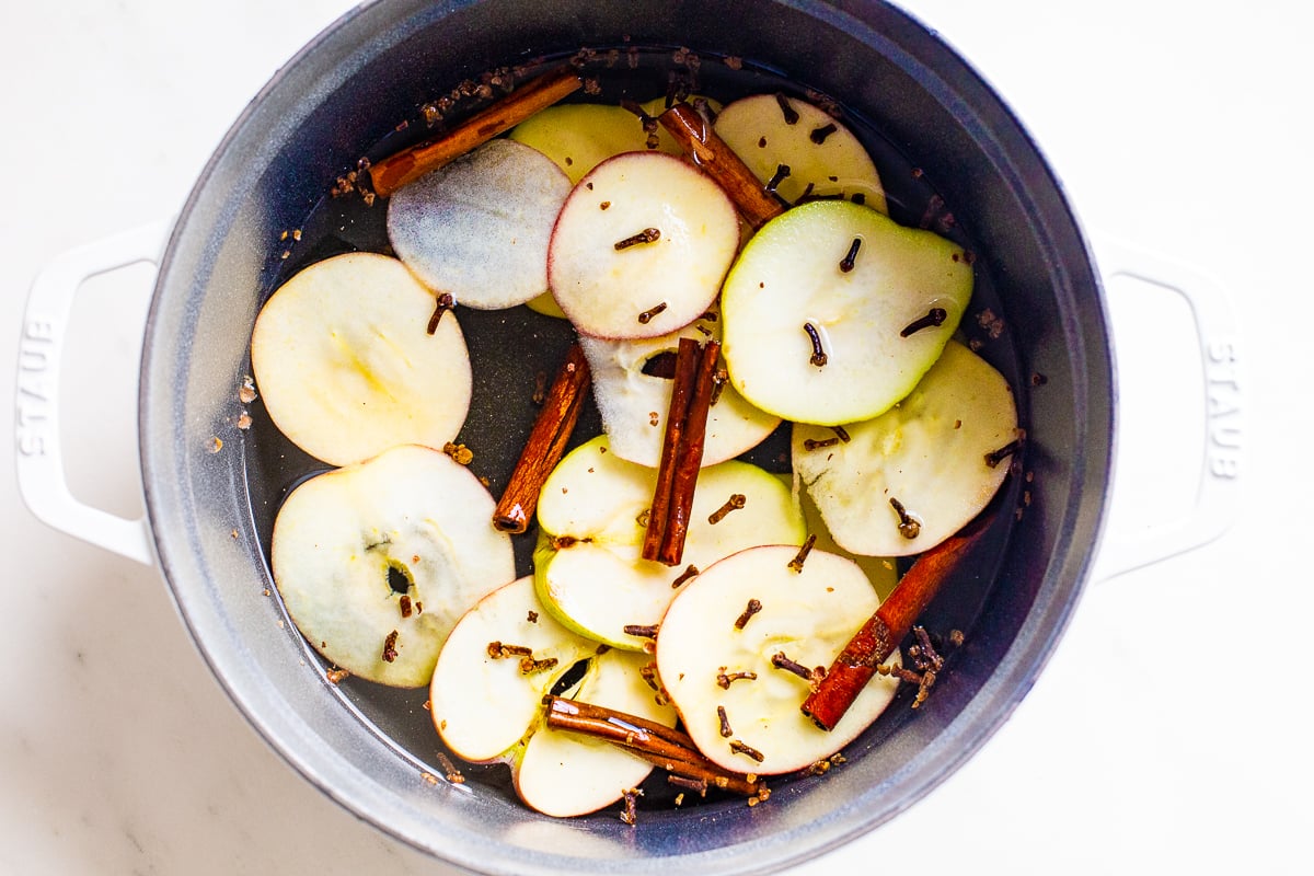 A cast iron simmer pot filled with stovetop potpourri of sliced apples, cinnamon sticks and more!