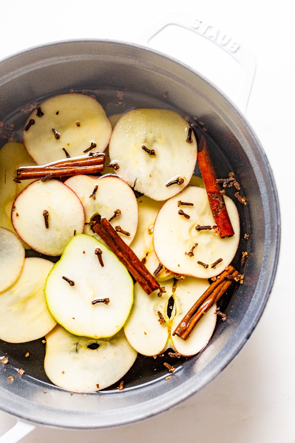 A cast iron simmer pot filled with stovetop potpourri of sliced apples, cinnamon sticks and more!