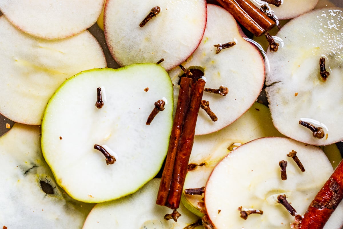 A cast iron simmer pot filled with stovetop potpourri of sliced apples, cinnamon sticks and more!